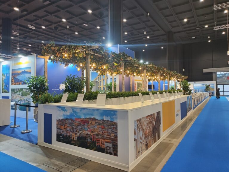 Reception dello stand Campania con installazione scenografica di piante e limoni, simbolo della costiera amalfitana