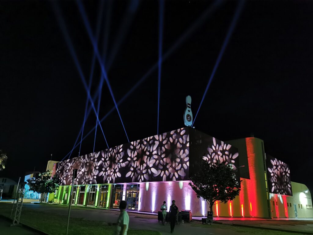 Struttura aziendale vista dall'esterno di notte, con fari e illuminazione che evidenziano l'architettura e creano un'atmosfera luminosa per l'evento aziendale Dicembre 2023 a Milano.